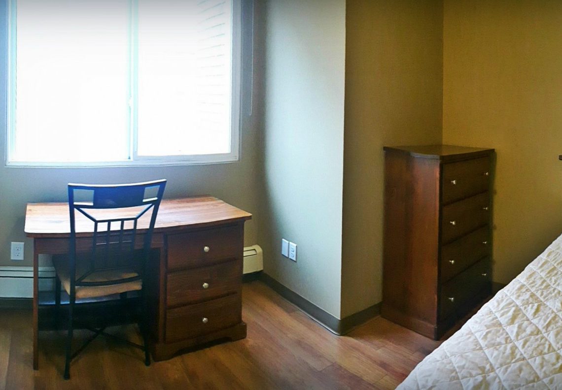 student apartment room with bed and desk