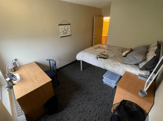 Student residence bedroom with bed, desk, and nightstand