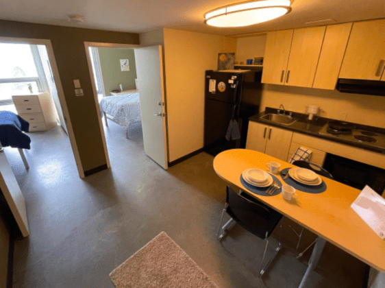 Student residence kitchen area with table, fridge and sink