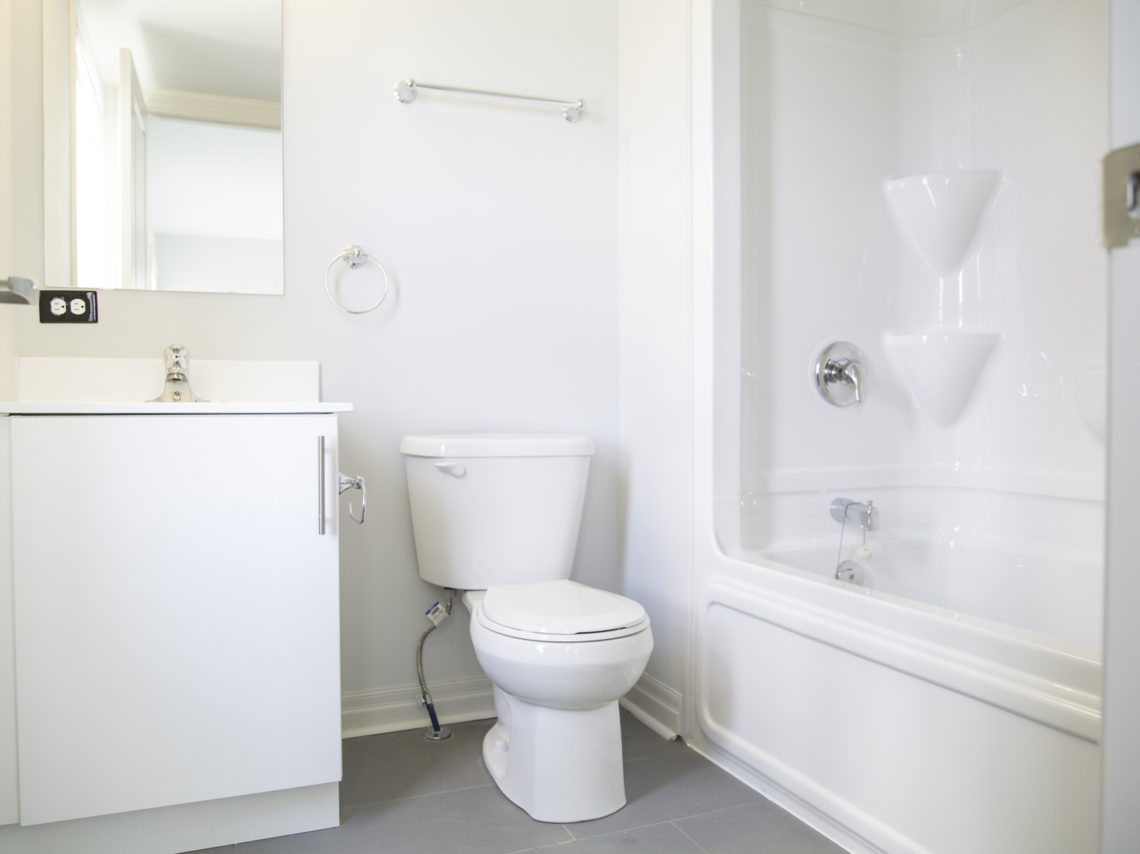 white bathroom with toilet, sink and shower