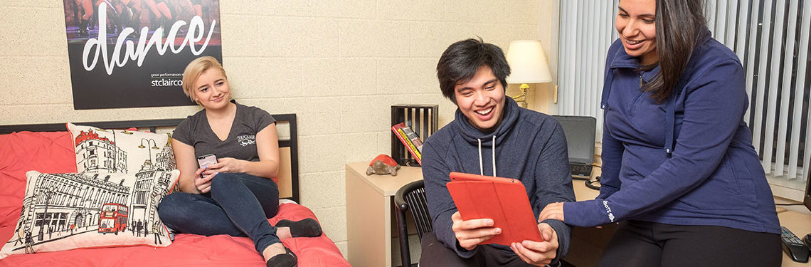 Three students sitting in residence room smiling