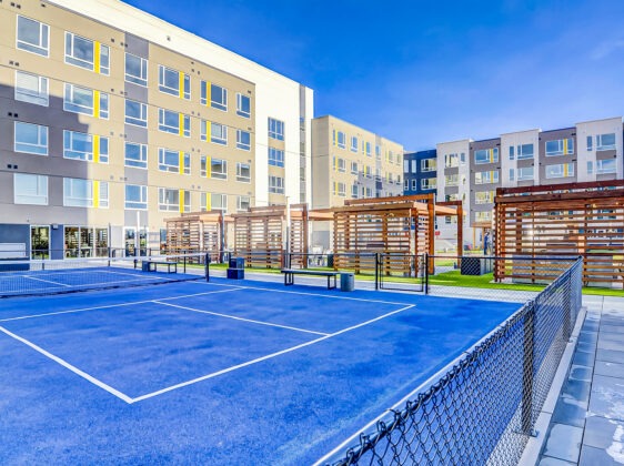 Blue tennis court facing Aria exterior building.