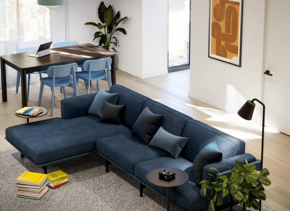 Livingroom with blue suede sectional couch, dining area with table and 4 chairs, and 3 large tropical plants.