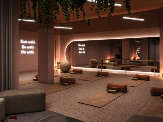 Contemporary design yoga studio in warm terracotta colours, with yoga mats and pillows rolled out under large oval mirror.